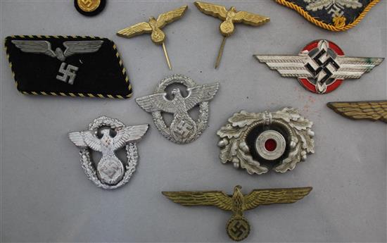 A collection of various German Third Reich cap badges, cloth badges and pins